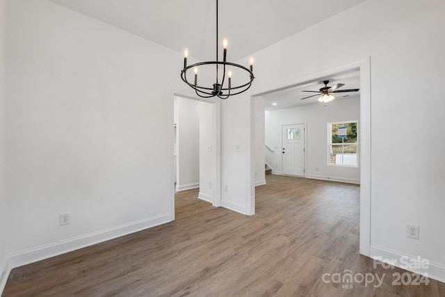 unfurnished dining area with hardwood / wood-style flooring and ceiling fan with notable chandelier