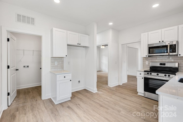 kitchen with appliances with stainless steel finishes, white cabinetry, and light wood-type flooring