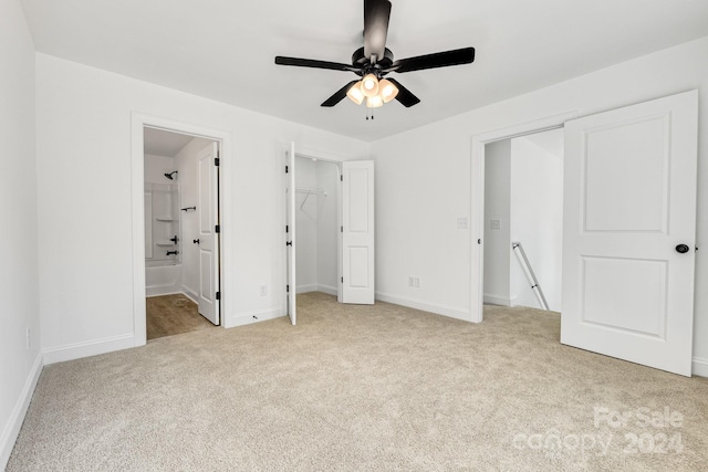 unfurnished bedroom featuring connected bathroom, light carpet, and ceiling fan