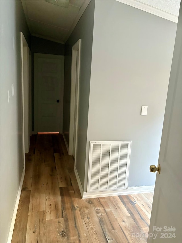 hall with light hardwood / wood-style flooring and crown molding