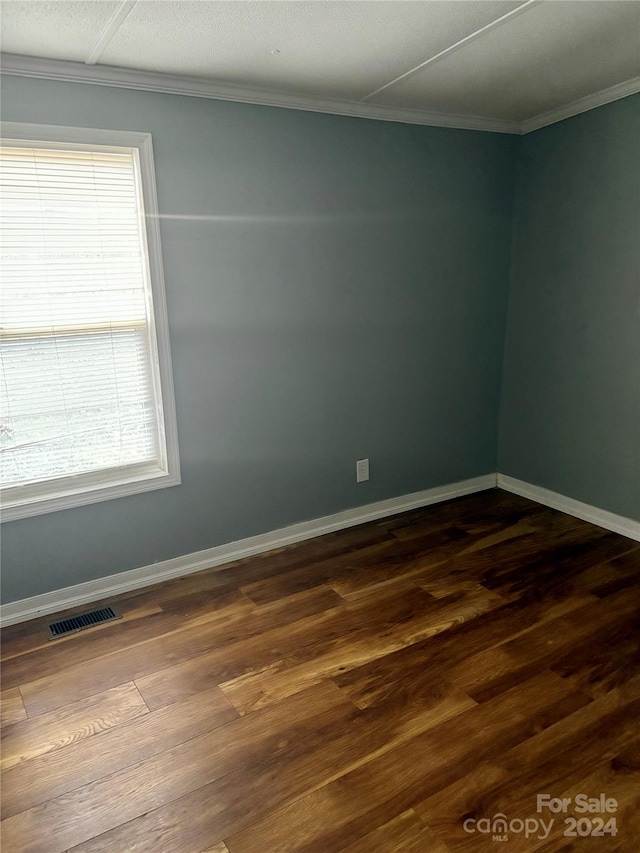 spare room featuring hardwood / wood-style floors, a wealth of natural light, and ornamental molding