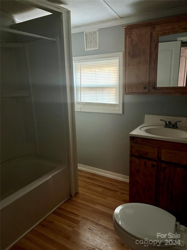 full bathroom featuring wood-type flooring, bathing tub / shower combination, ornamental molding, vanity, and toilet