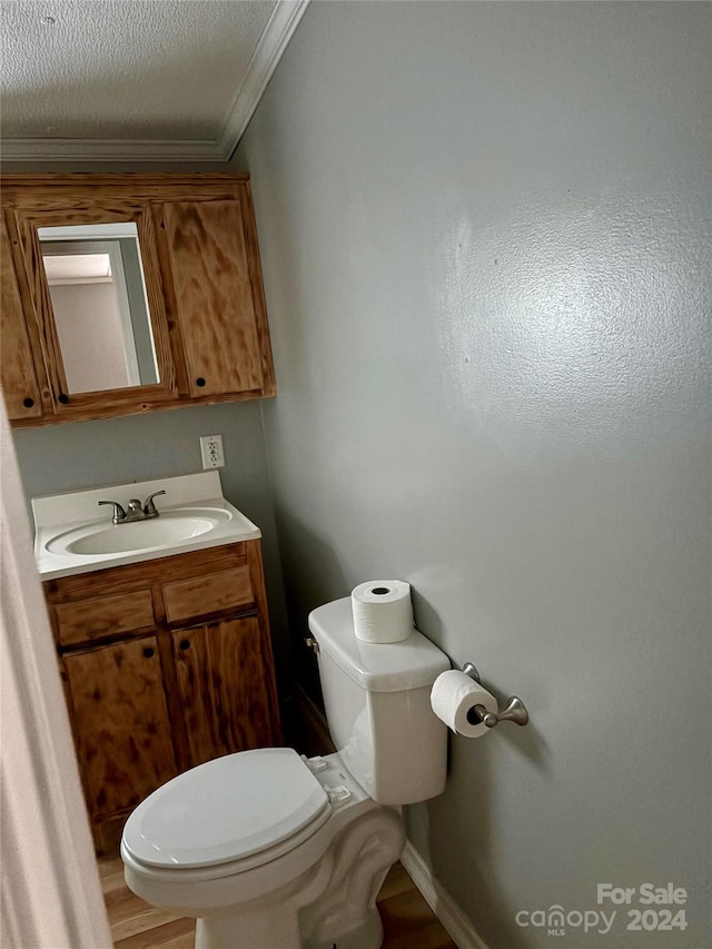 bathroom featuring ornamental molding, vanity, hardwood / wood-style flooring, and toilet