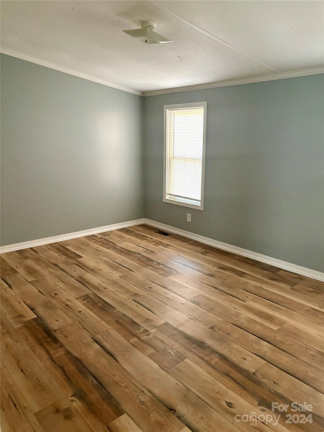 spare room with hardwood / wood-style flooring and crown molding