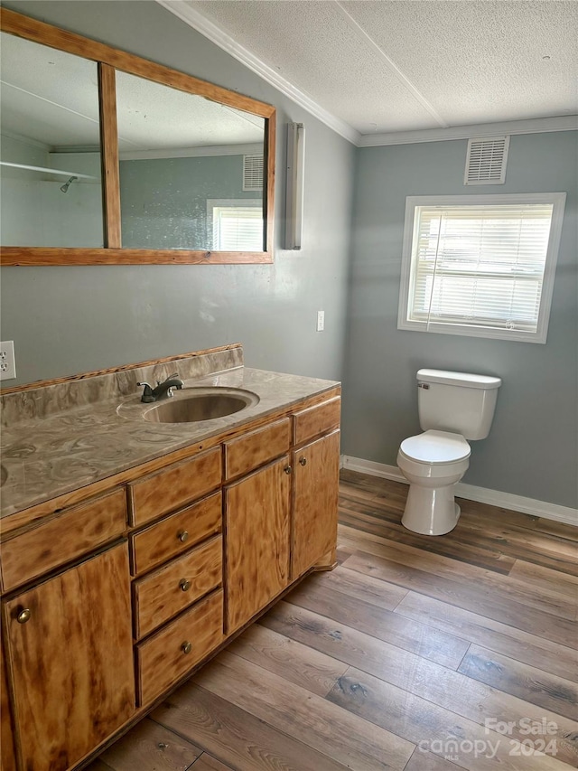 bathroom featuring a textured ceiling, hardwood / wood-style floors, vanity, crown molding, and toilet