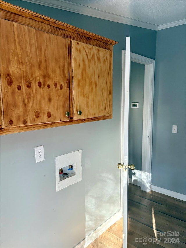 laundry area featuring dark wood-type flooring, washer hookup, cabinets, and crown molding