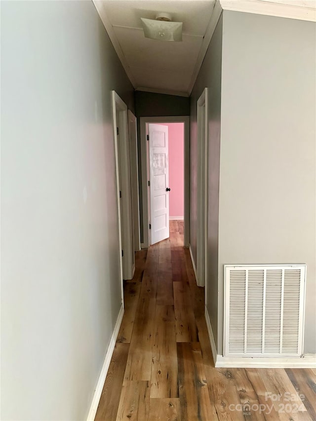 hallway featuring ornamental molding and light hardwood / wood-style floors