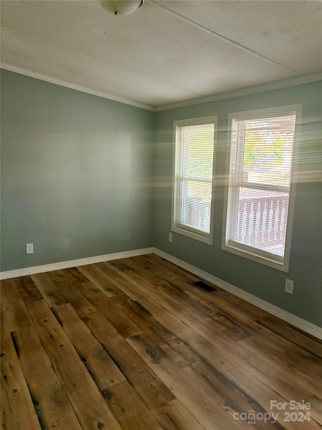 empty room featuring hardwood / wood-style flooring and crown molding