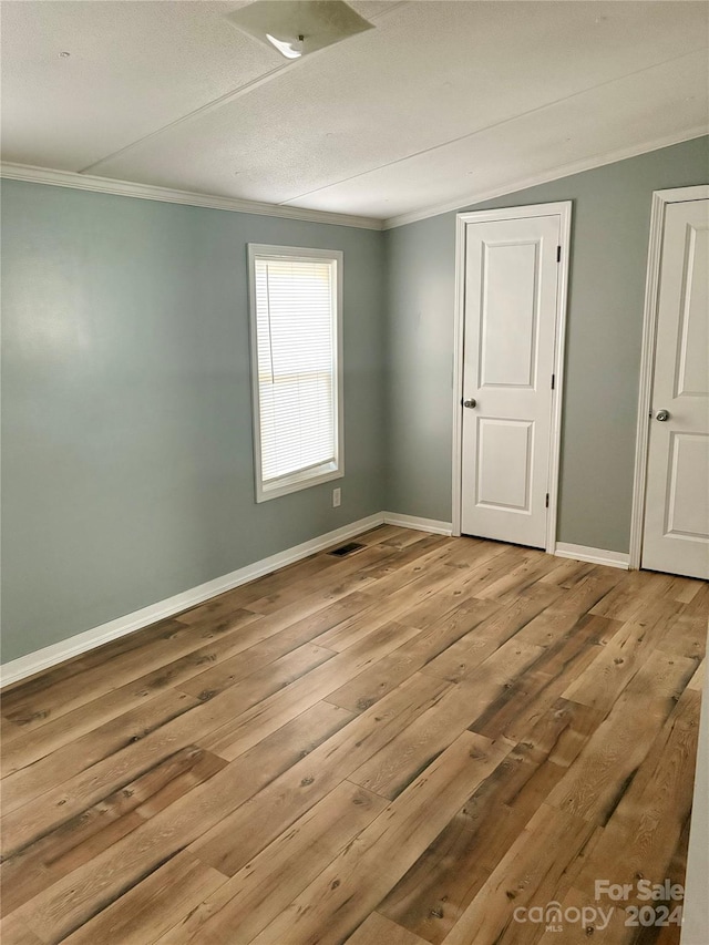 empty room with ornamental molding and light hardwood / wood-style floors