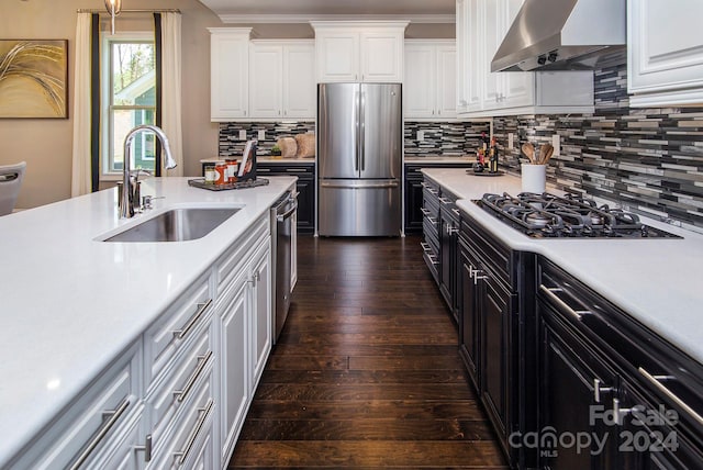 kitchen featuring wall chimney range hood, sink, white cabinets, appliances with stainless steel finishes, and dark hardwood / wood-style flooring