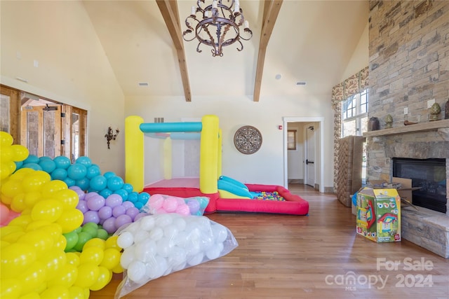 playroom featuring hardwood / wood-style floors, beam ceiling, high vaulted ceiling, and a fireplace