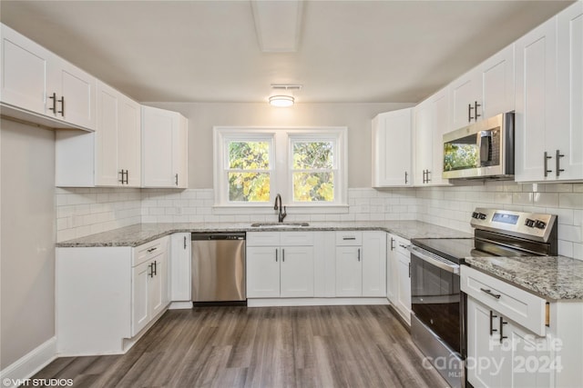 kitchen with appliances with stainless steel finishes, sink, dark hardwood / wood-style flooring, white cabinets, and decorative backsplash