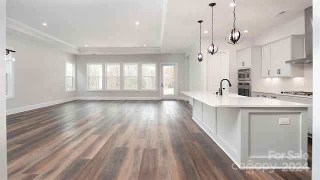 kitchen with a large island with sink, wall chimney exhaust hood, and a healthy amount of sunlight