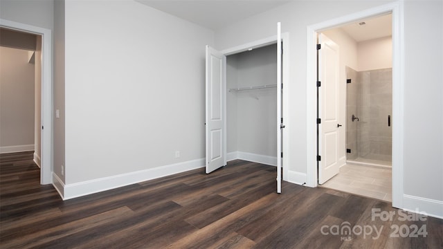 unfurnished bedroom featuring a closet, connected bathroom, and dark hardwood / wood-style flooring