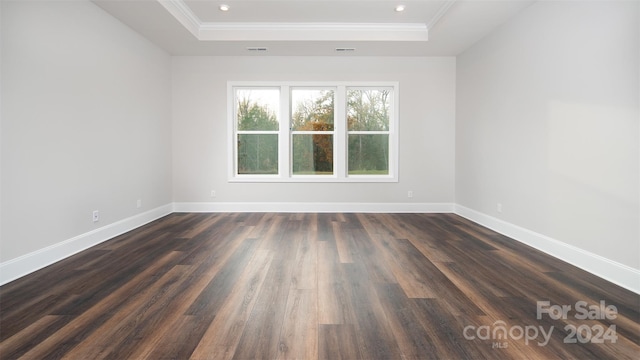 unfurnished room with a raised ceiling, dark hardwood / wood-style floors, and ornamental molding