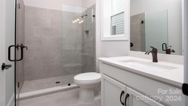 bathroom featuring toilet, vanity, tile patterned floors, and a shower with shower door