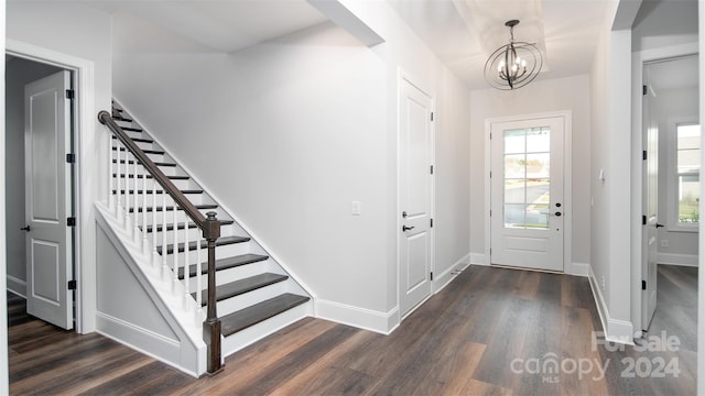 entrance foyer with dark wood-type flooring, a healthy amount of sunlight, and an inviting chandelier