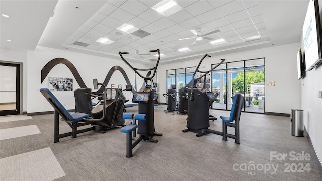 gym featuring a paneled ceiling, ceiling fan, and light colored carpet