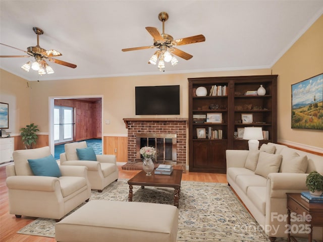 living room with crown molding, ceiling fan, a fireplace, and light hardwood / wood-style floors