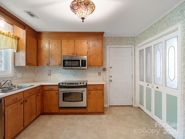 kitchen with stainless steel appliances, ornamental molding, sink, and a textured ceiling