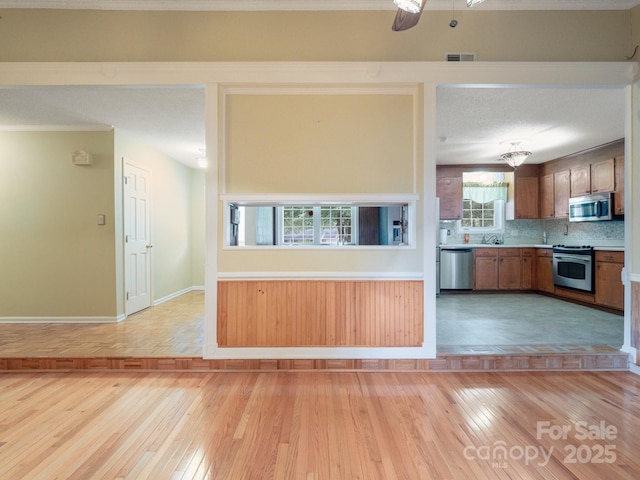 kitchen featuring stainless steel appliances, sink, decorative backsplash, and light wood-type flooring