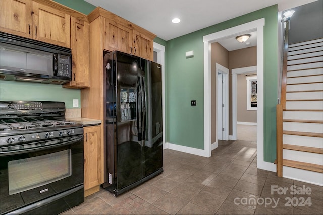 kitchen featuring light brown cabinetry, tile patterned floors, and black appliances