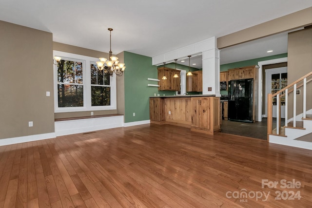 unfurnished living room featuring dark hardwood / wood-style floors and an inviting chandelier