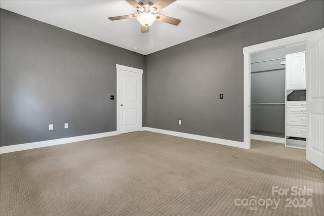 unfurnished bedroom featuring light carpet, a closet, and ceiling fan