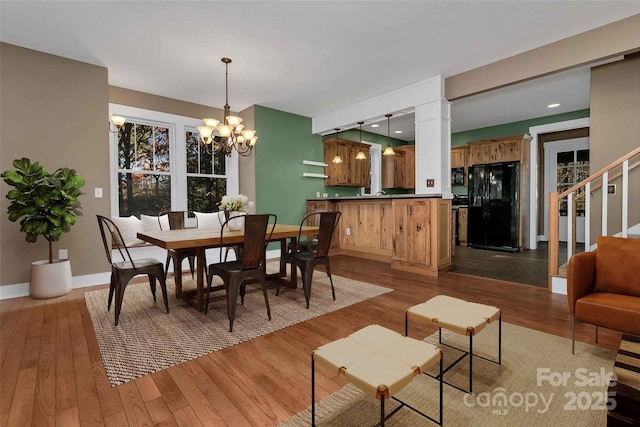 dining space with decorative columns, baseboards, a notable chandelier, and wood-type flooring