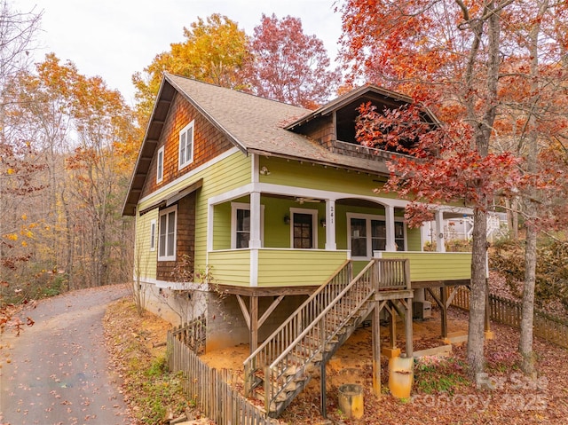view of front of home with central AC, stairway, aphalt driveway, covered porch, and roof with shingles