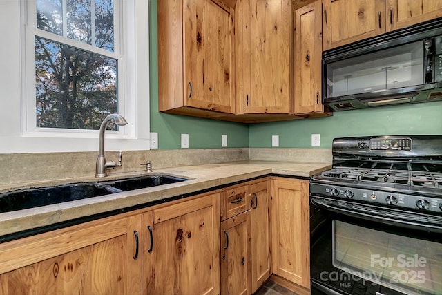 kitchen with light countertops, a sink, and black appliances
