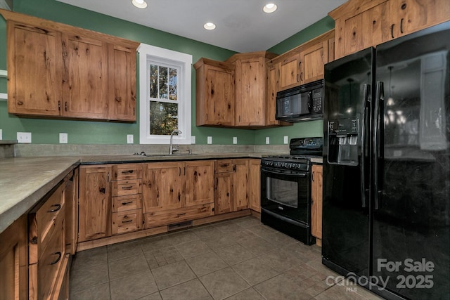 kitchen with a sink, black appliances, brown cabinets, dark tile patterned floors, and recessed lighting