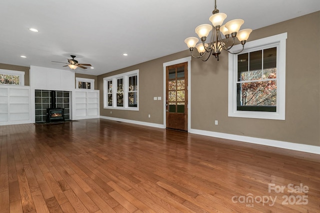 unfurnished living room with recessed lighting, wood finished floors, baseboards, built in shelves, and ceiling fan with notable chandelier