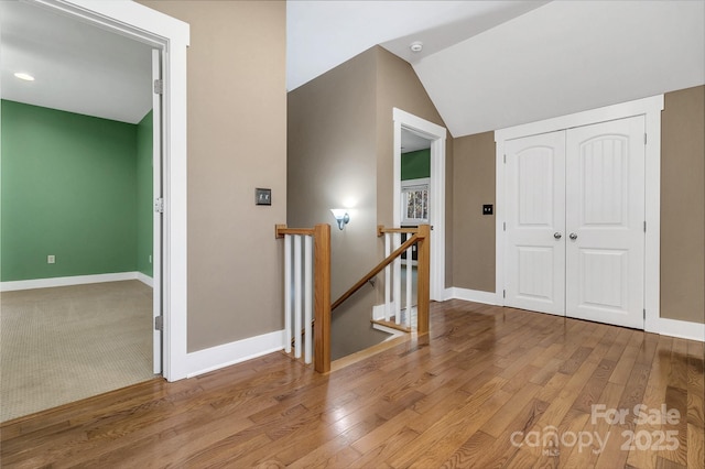 interior space featuring lofted ceiling, wood finished floors, and baseboards