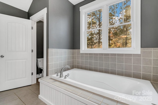 full bath with a garden tub, tile patterned flooring, and toilet