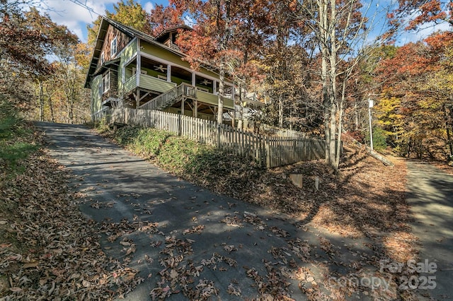 rear view of property featuring fence, aphalt driveway, and stairs