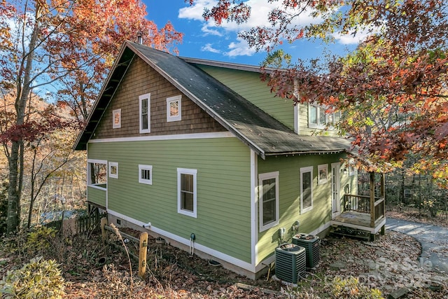 view of side of property featuring cooling unit and roof with shingles