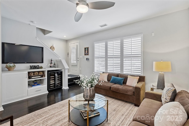 living room with wine cooler, dark hardwood / wood-style flooring, ceiling fan, and bar