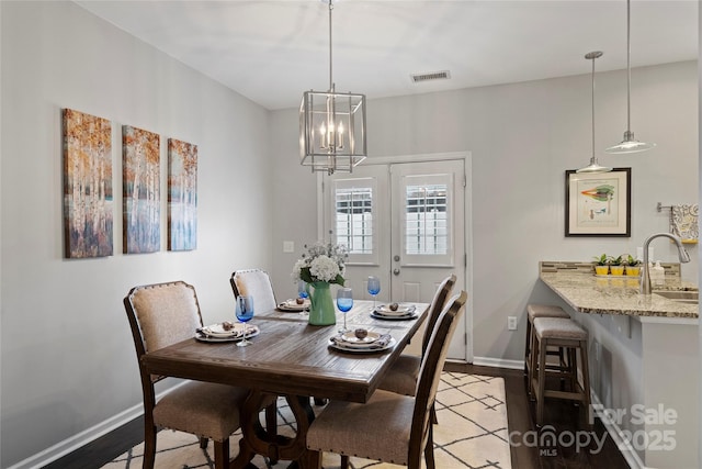 dining space with an inviting chandelier, sink, wood-type flooring, and french doors