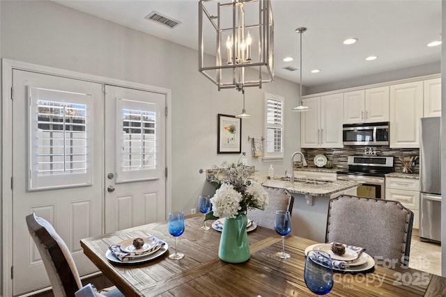 dining space with french doors, an inviting chandelier, and sink