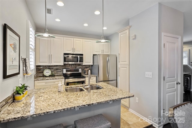 kitchen with appliances with stainless steel finishes, tasteful backsplash, a kitchen breakfast bar, hanging light fixtures, and light stone counters