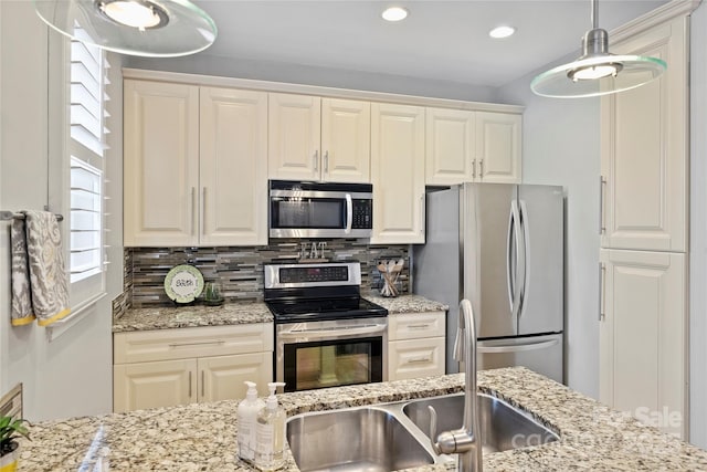 kitchen featuring appliances with stainless steel finishes, light stone countertops, sink, and decorative backsplash