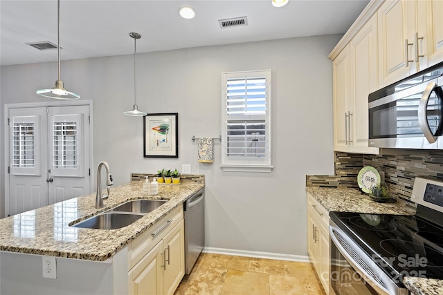 kitchen featuring appliances with stainless steel finishes, decorative light fixtures, sink, decorative backsplash, and light stone counters