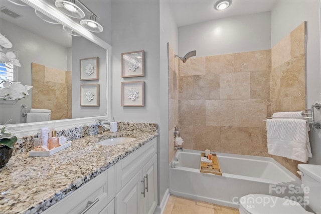 full bathroom with vanity, tiled shower / bath combo, and toilet