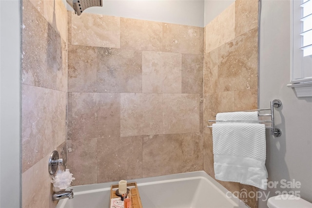 bathroom featuring tiled shower / bath and toilet