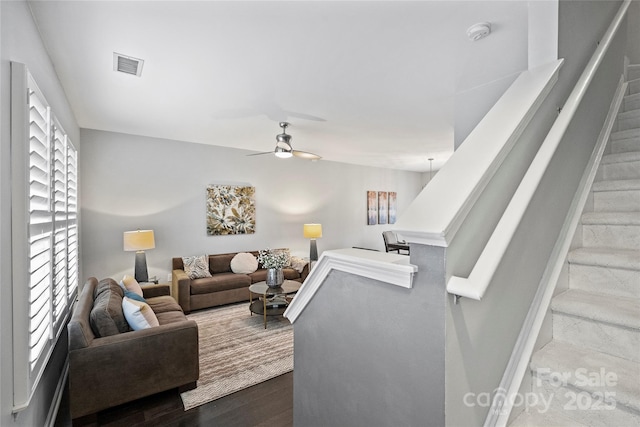 living room featuring dark wood-type flooring and ceiling fan