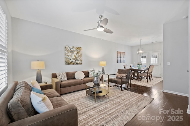 living room with dark hardwood / wood-style flooring and ceiling fan with notable chandelier