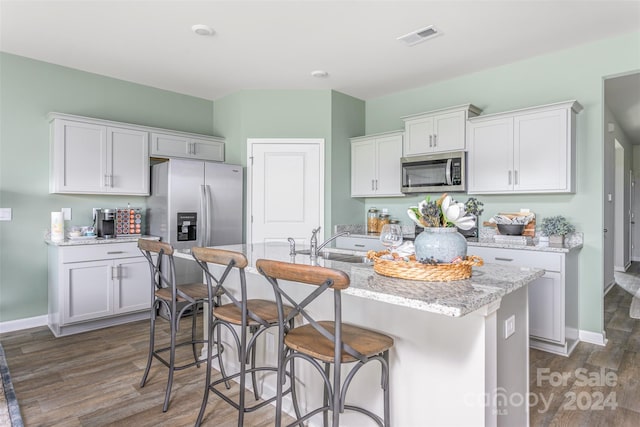 kitchen featuring an island with sink, white cabinetry, stainless steel appliances, and dark hardwood / wood-style flooring