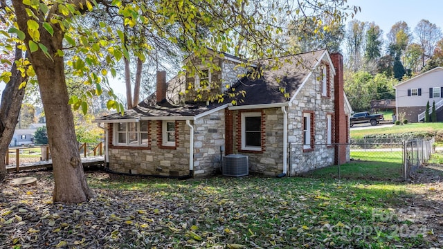 exterior space featuring cooling unit and a front yard