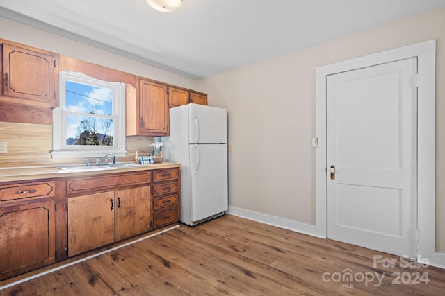 kitchen with hardwood / wood-style floors, white refrigerator, tasteful backsplash, and sink